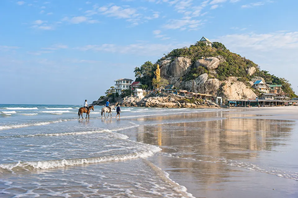 Hua Hin beach at low tide, horse riders on the sand